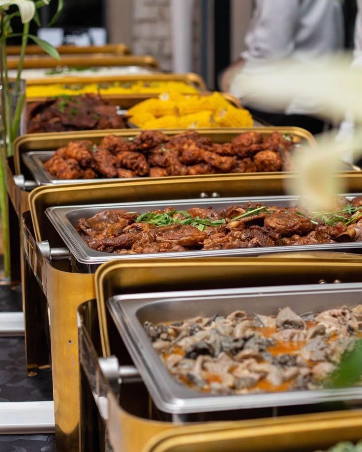 Gold chafing dishes with roast meats and sides at a buffet